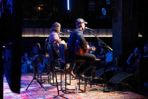 A backstage view of Dierks Bentley and Jon Nite playing guitar together on stage.