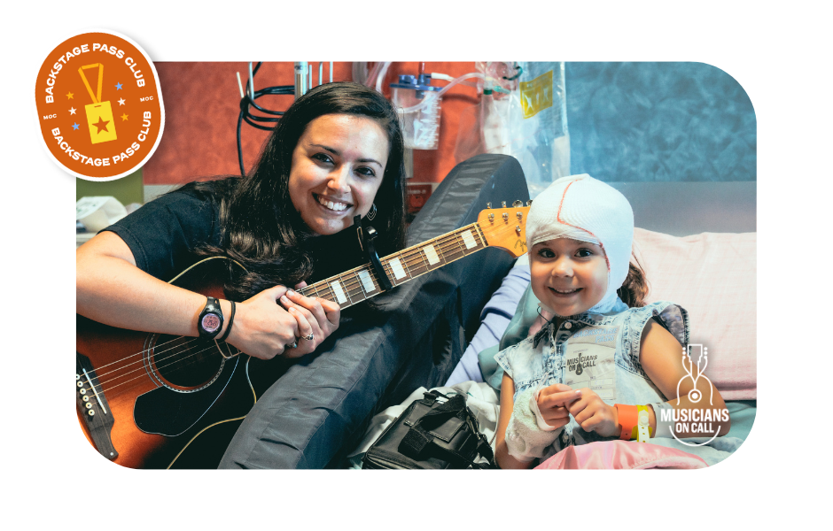 Musicians On Call Volunteer Musician Kelli sits with a smiling patient. The patient is holding her backstage pass given to her after a Bedside program
